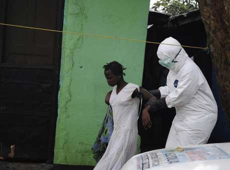 Agente de saúde ajuda paciente com ebola na Libéria Foto: James Giahyue / Reuters