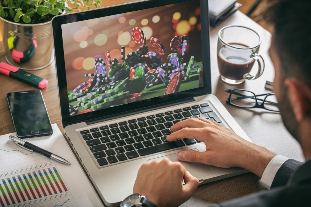 online gambling concept man at work casino chips on a computer screen